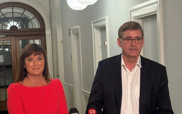 Sophie Løhde og Jørgen Skadborg ved doorsteppressemøde foran bord og ser mod den fremmødte presse og taler