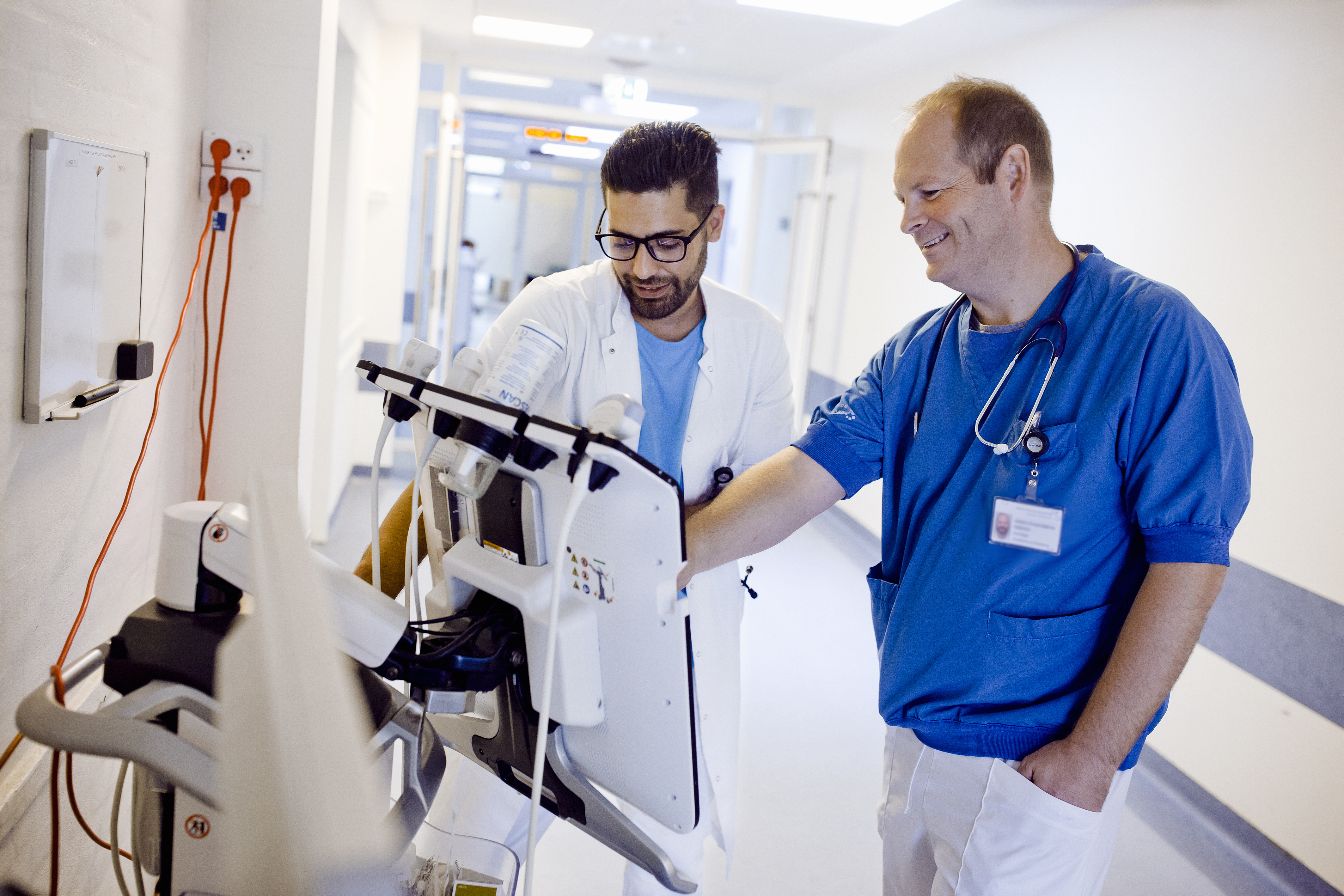 To smilende overlæger der gør brug af en af hospitalets maskiner  