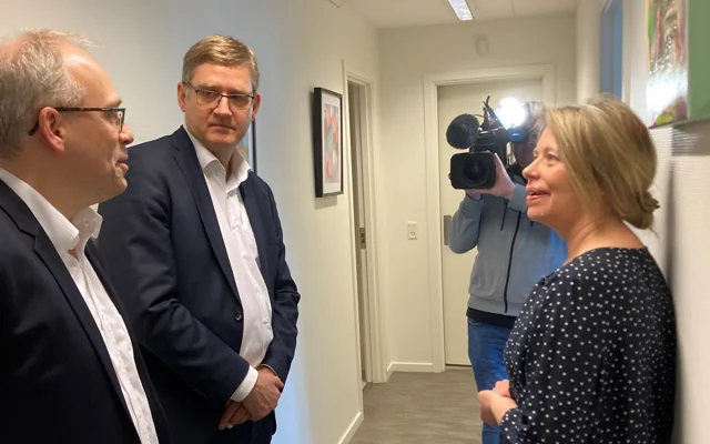 PLO's direktøro og formand står i lægeklinik i Guldborgsund, Kamera filmer i baggrunden.