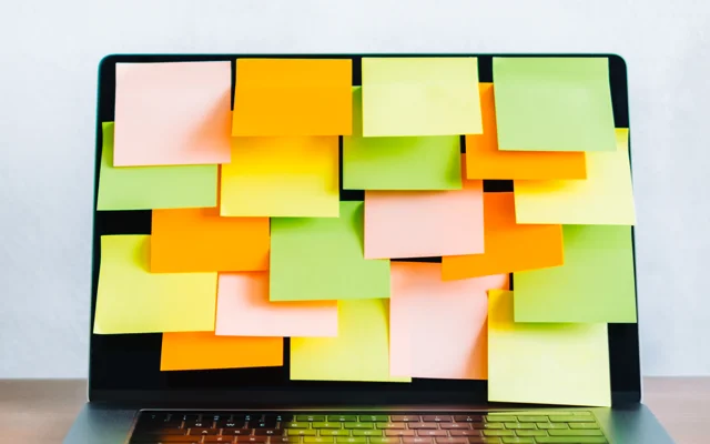 Post its på skærmen af en bærbar computer på et skrivebord